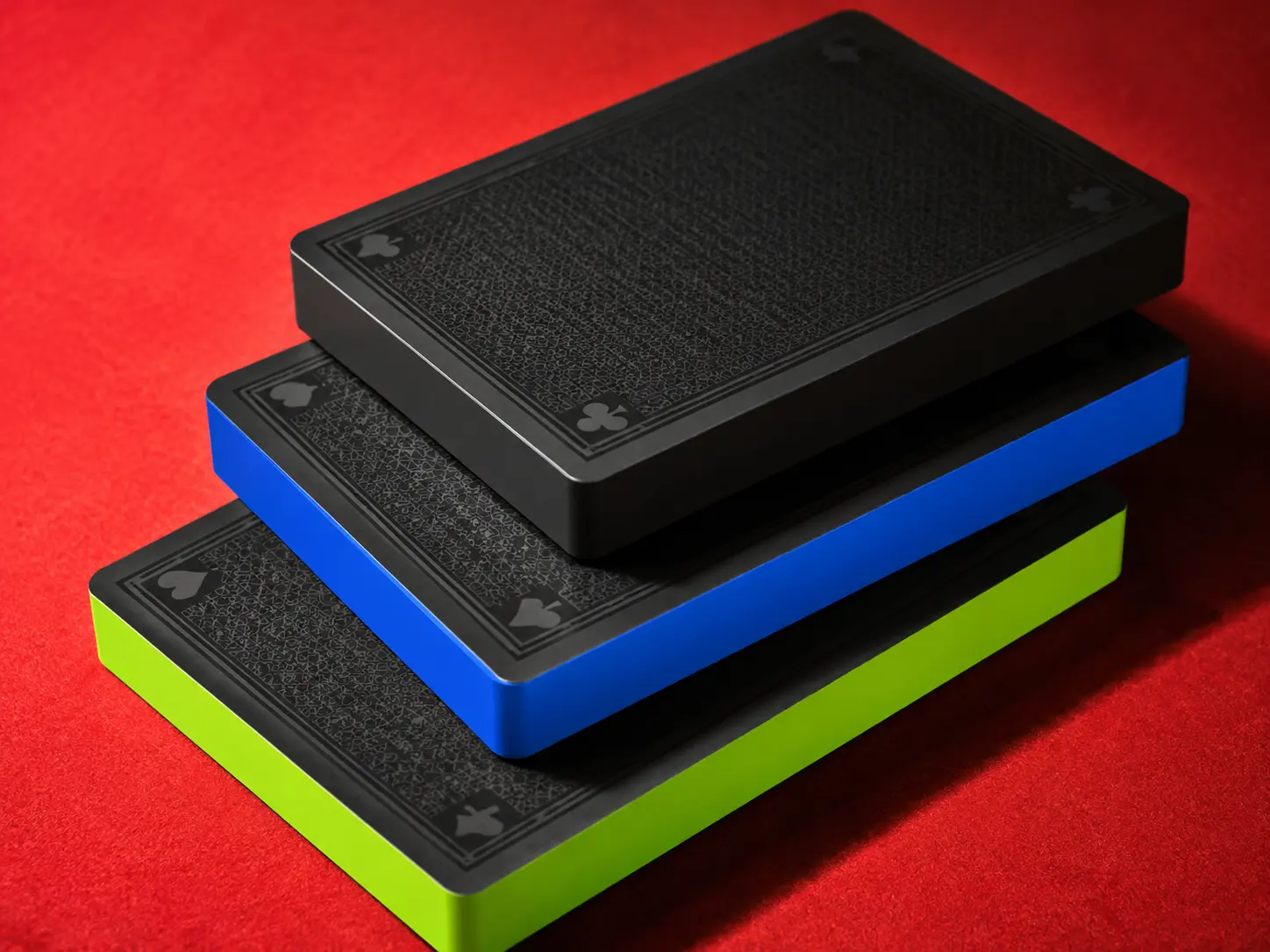 Three thick black card slabs with cobalt and lime edges stacked on red felt